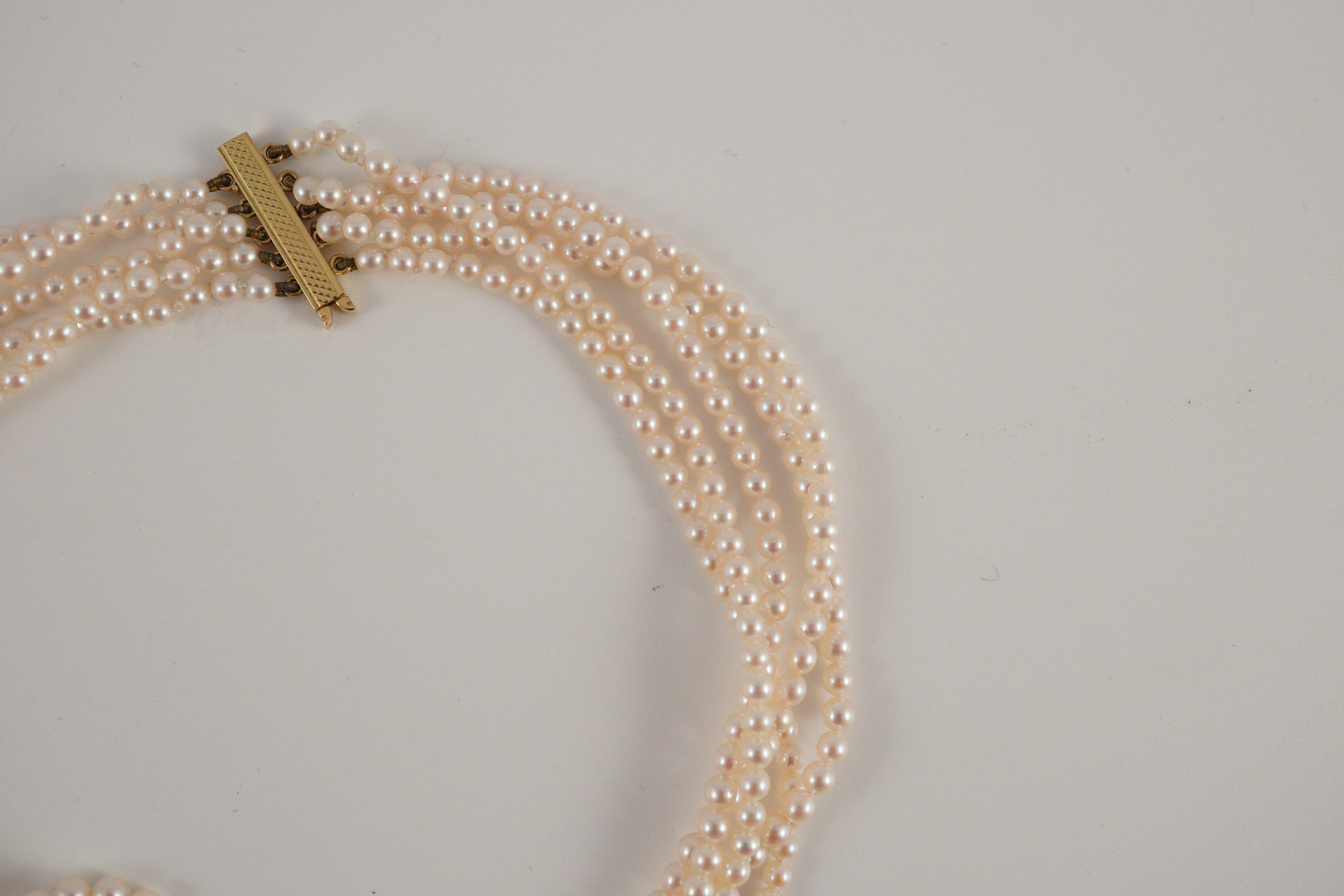 A quintuple strand seed pearl choker necklace, with pierced gold, platinum and diamond cluster set quatrefoil shaped clasp